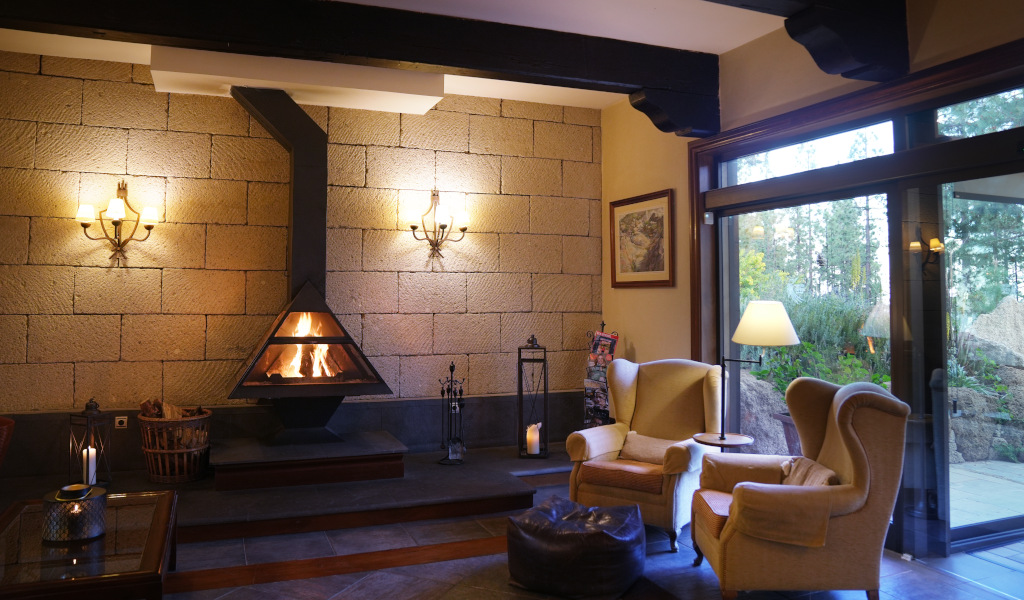 Sala de estar con chimenea y sillones cerca de ventana con vista al exterior en Tenerife.