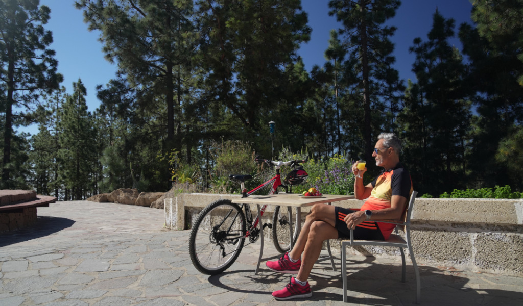 Hombre con bebida junto a bicicleta en bosque de Tenerife.