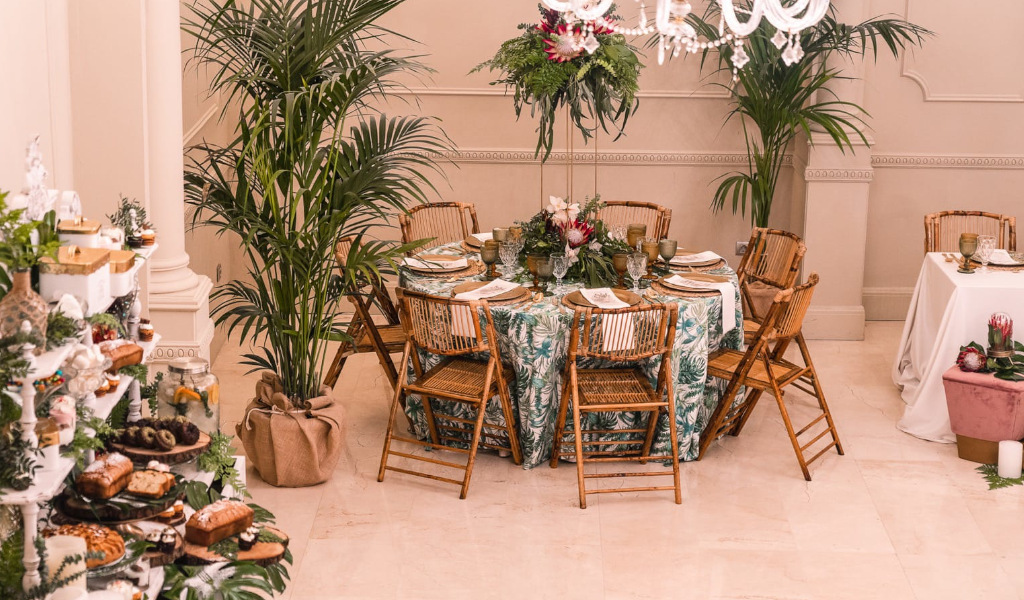 Mesa decorada para un evento en Tenerife con sillas de madera y plantas ornamentales.