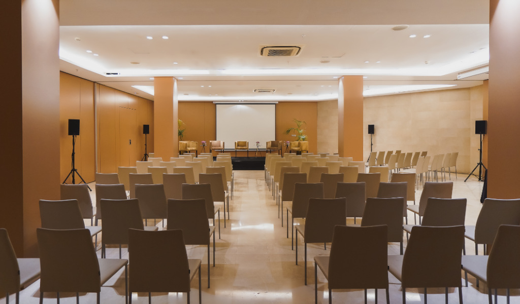 Sala de conferencias vacía con sillas y escenario en Tenerife.