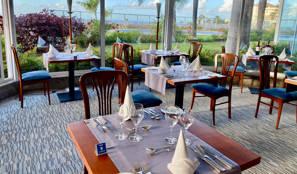 Restaurante en Tenerife con mesas preparadas y vista al jardín.