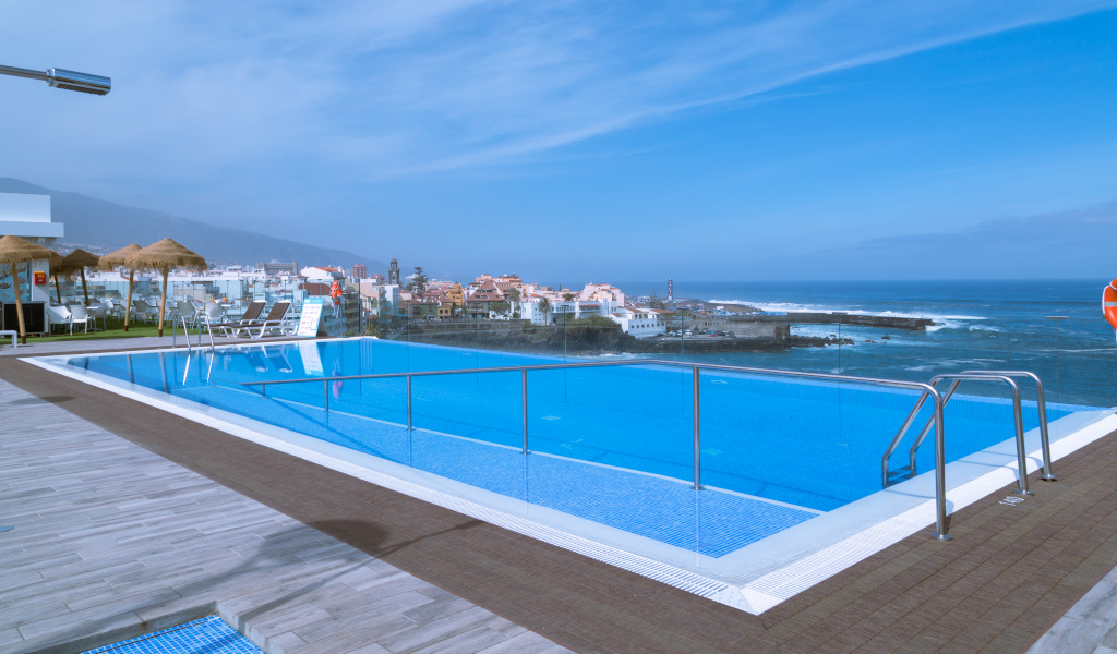 Piscina infinita con vista al mar y edificios en Puerto de la Cruz, Tenerife.