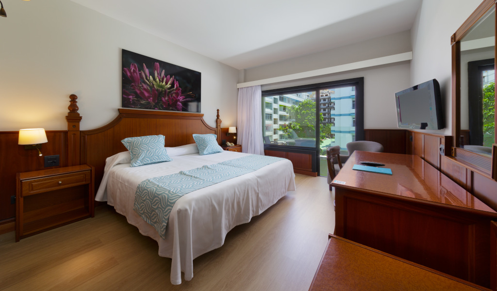 Habitación de hotel en Tenerife con cama doble, TV y ventana grande.