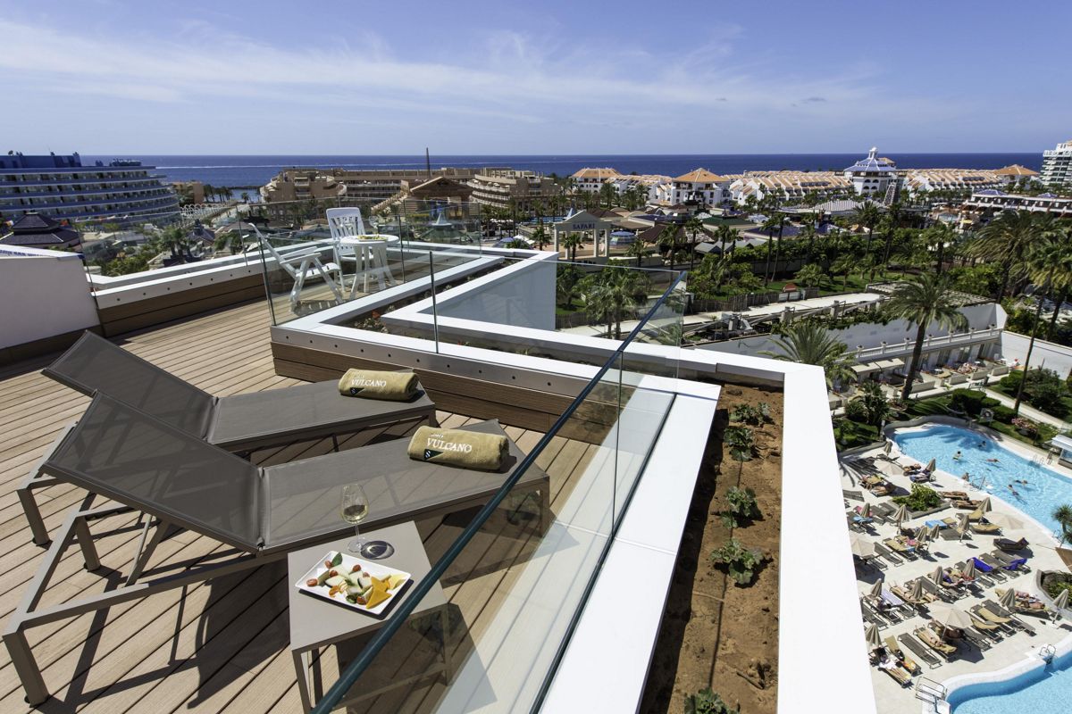 Terraza con tumbonas, vista al mar y piscina en un hotel de Tenerife.