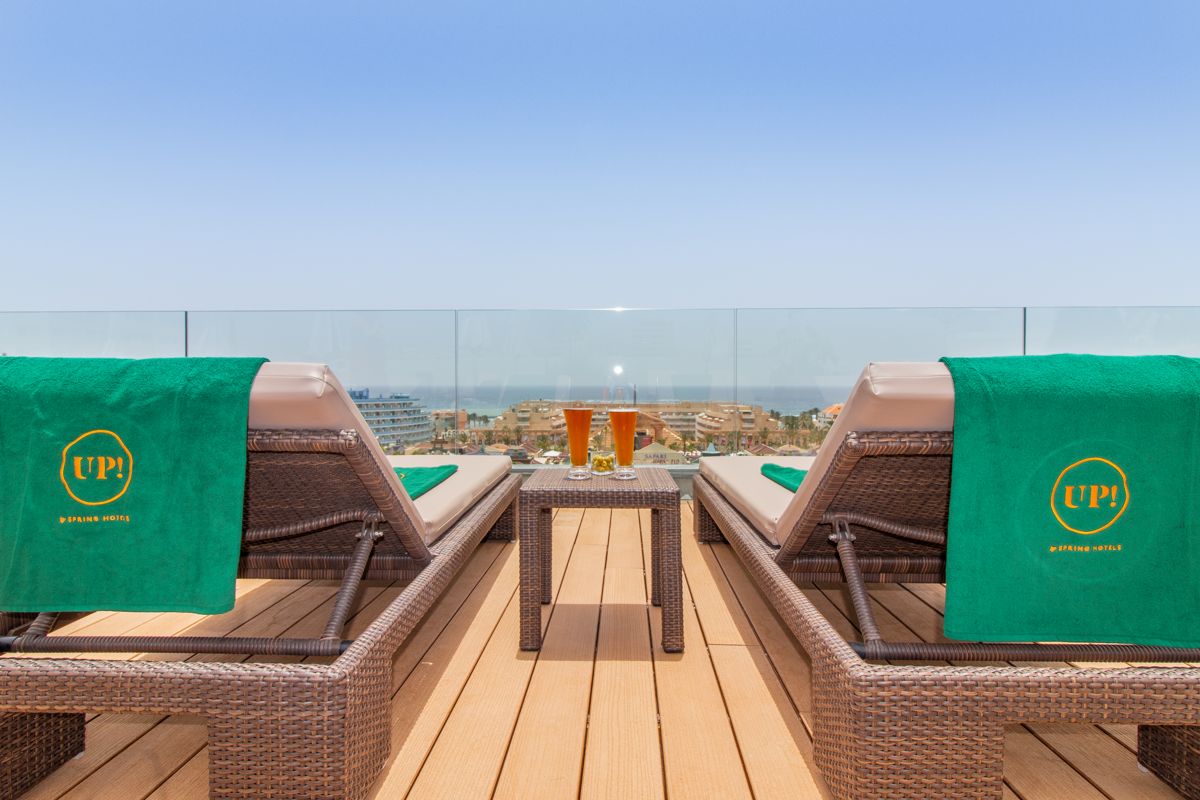 Dos tumbonas con toallas verdes y bebidas en terraza con vista a Tenerife.