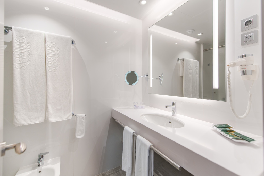 Baño moderno con toallas grabadas SPRING, espejo y secador.