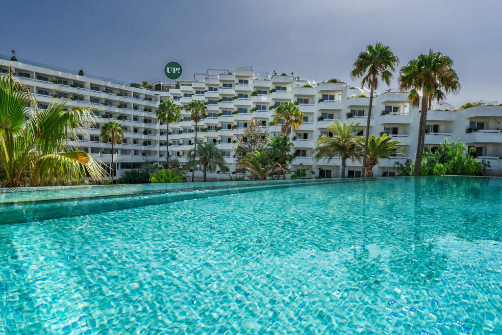 Piscina frente a edificio rodeado de palmeras en Tenerife.