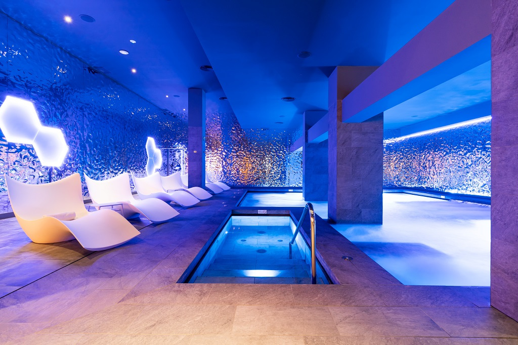 Área de spa iluminada con sillas modernas y piscina en hotel de Tenerife.