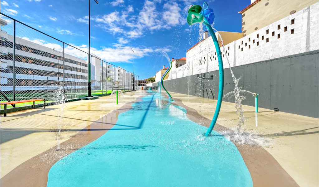 Zona de juegos acuática en Tenerife con chorros de agua y figura de flor grande.