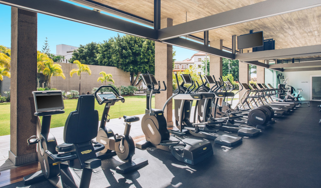 Gimnasio con equipos de ejercicio y vistas al jardín en Tenerife.