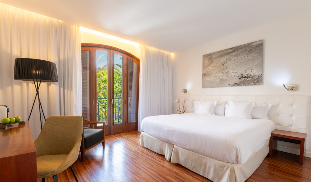 Habitación con cama doble, luz natural y puerta hacia jardín en Tenerife.