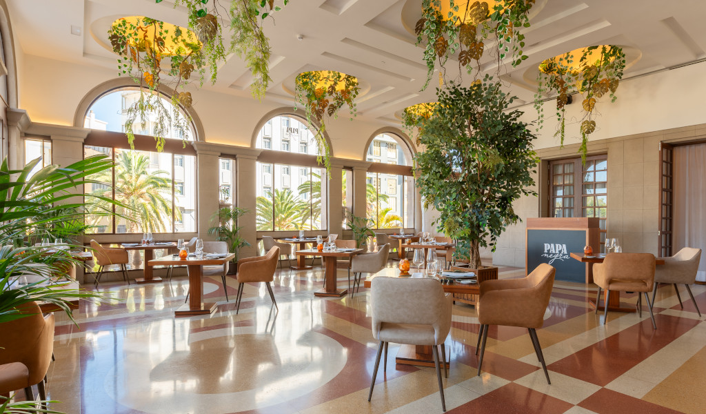 Restaurante elegantemente decorado en Tenerife con plantas colgantes y mesas preparadas.