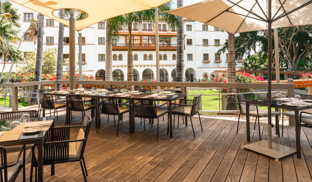 Terraza con mesas y sillas en un jardín de hotel en Tenerife.