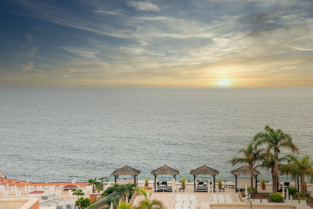 Terraza con cabañas frente al océano al atardecer en Tenerife.
