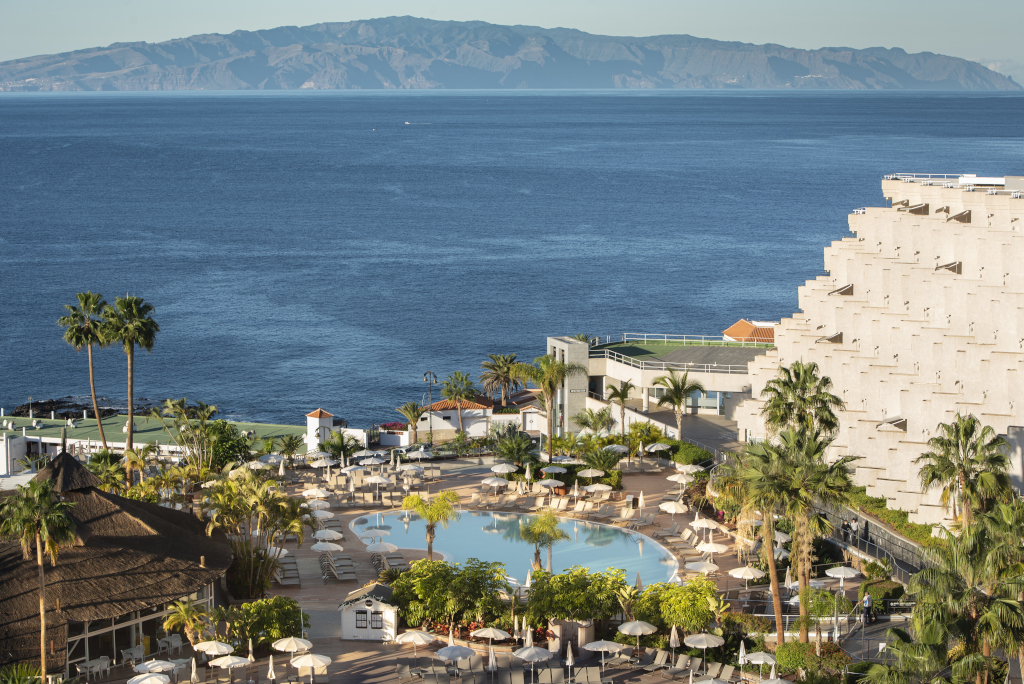 Piscina y palmeras con vista al océano en un hotel de Tenerife.