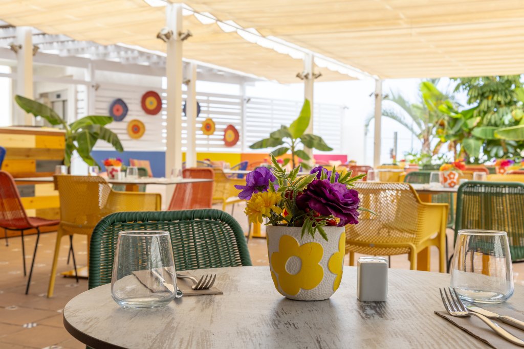 Mesa con flores y sillas coloridas en restaurante al aire libre en Tenerife.