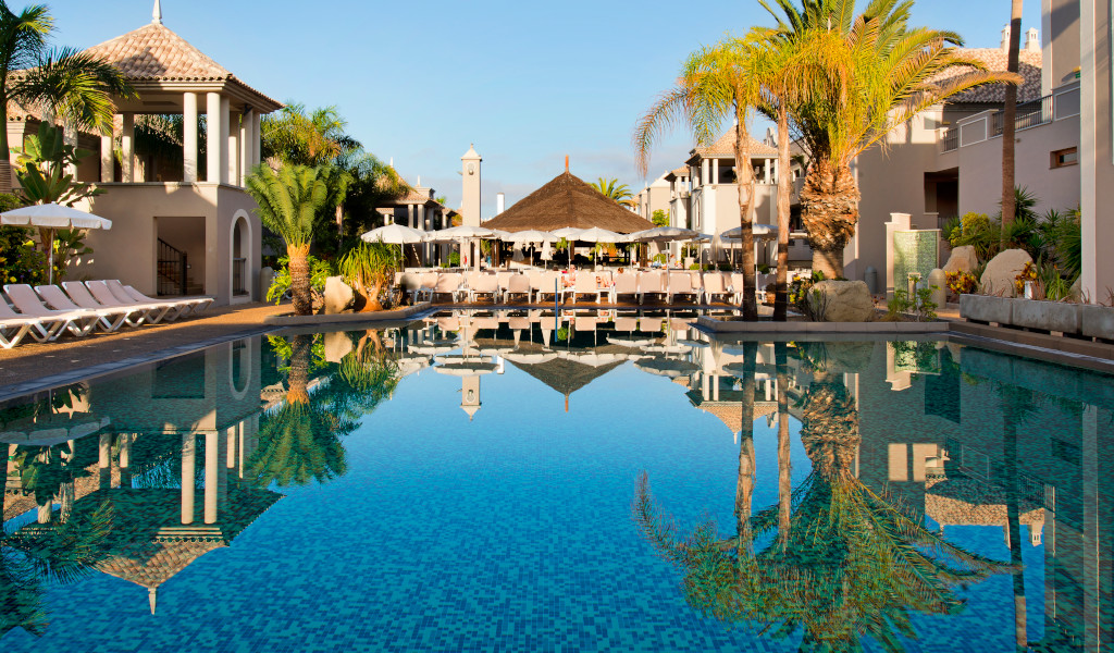 Piscina rodeada de palmeras y tumbonas en un resort de Tenerife.