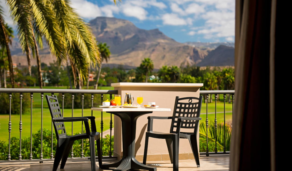 Desayuno en terraza con vista a montañas y palmeras en Tenerife.