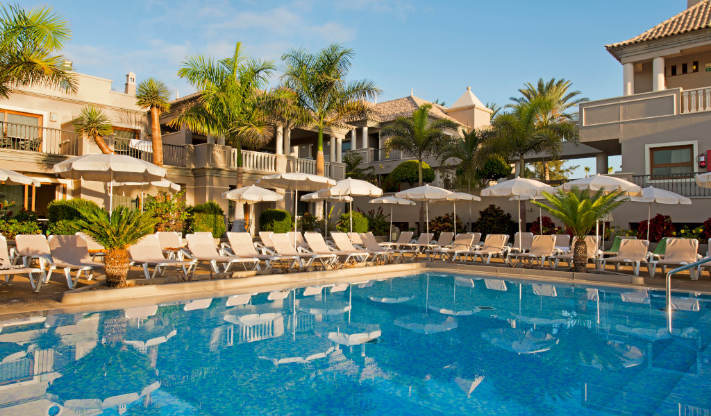 Piscina rodeada de tumbonas y sombrillas en un hotel de Tenerife.