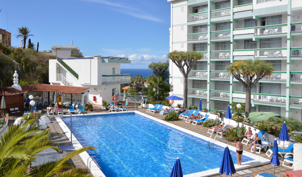 Piscina del hotel en Tenerife con tumbonas y vistas al océano.