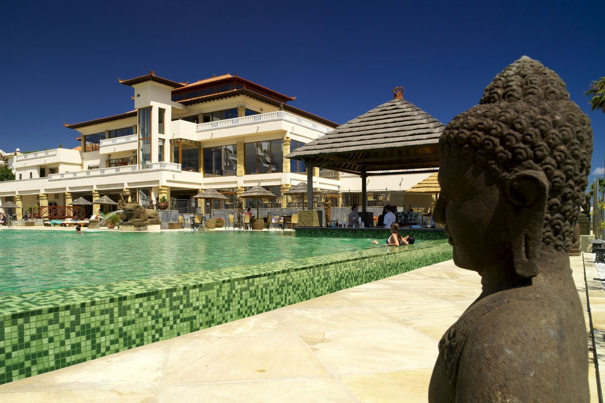 Piscina con estatua de Buda frente a edificio estilo oriental en Tenerife.