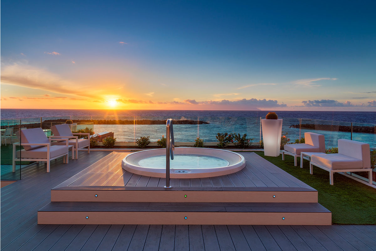 Atardecer sobre el mar desde una terraza con jacuzzi y sillas en Tenerife.