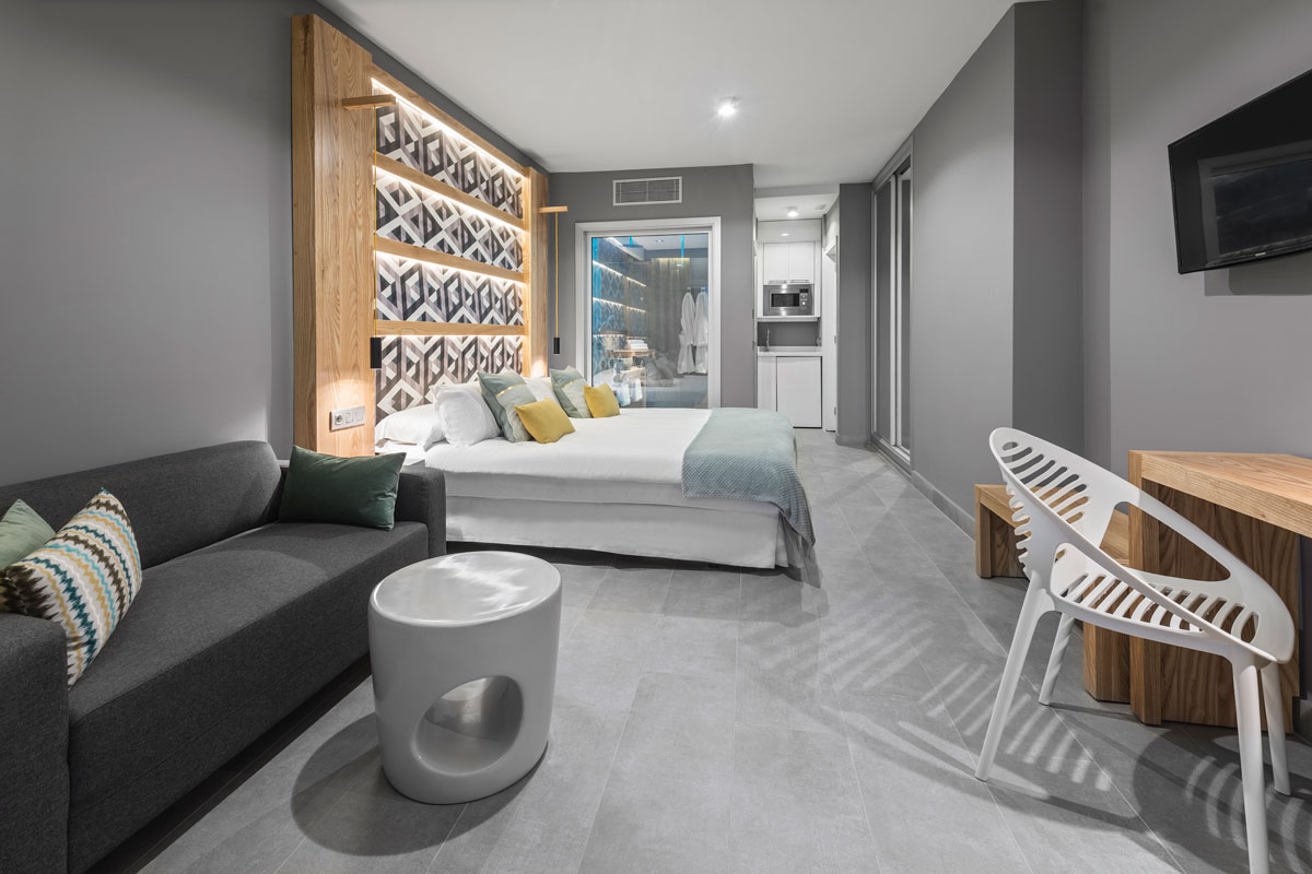 Habitación moderna con cama, sofá y cocina pequeña en Tenerife.
