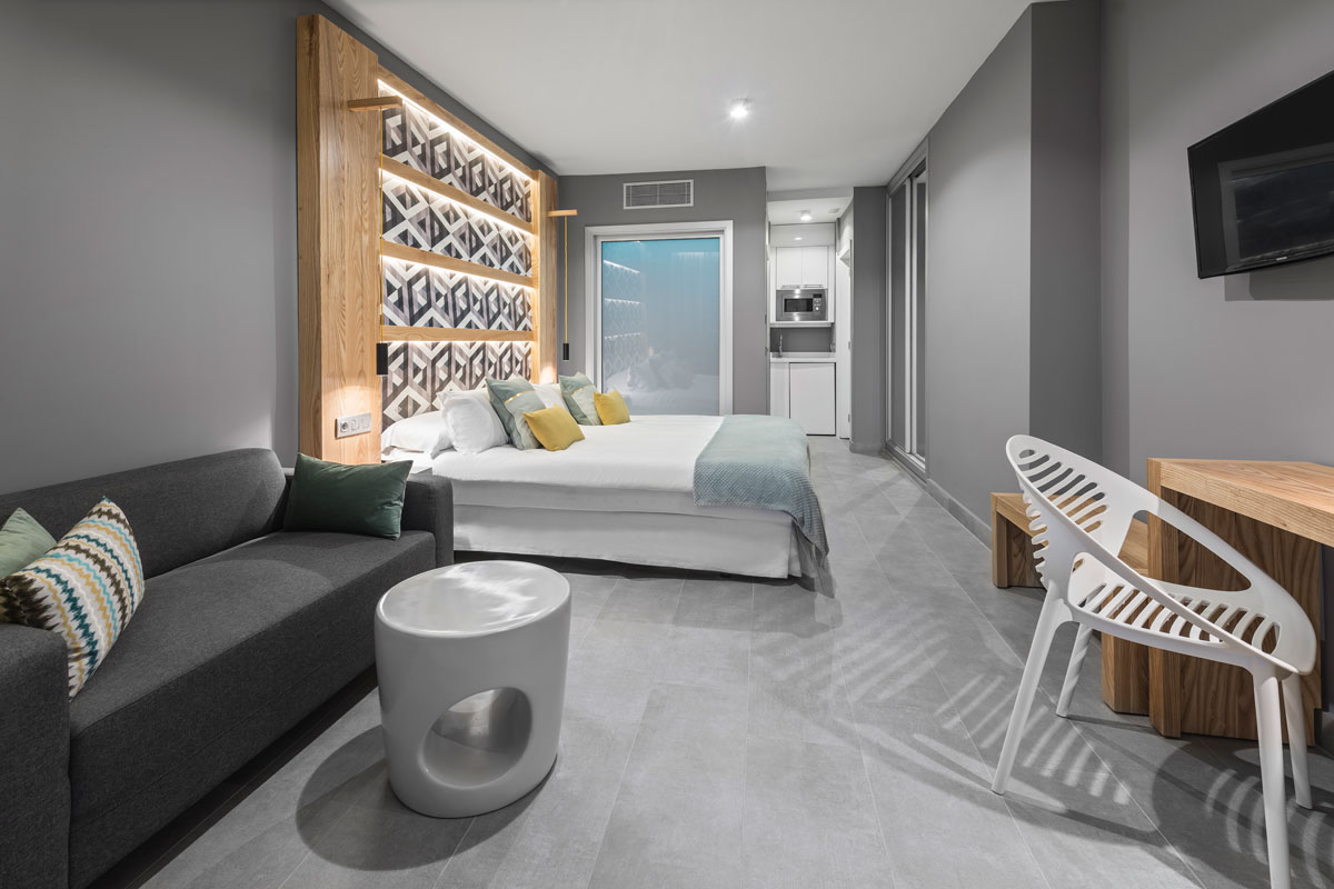Habitación moderna en hotel de Tenerife con cama, sofá y escritorio.