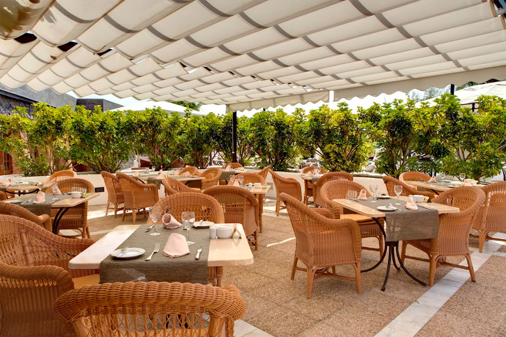 Terraza de restaurante en Tenerife con sillas de mimbre y mesas preparadas.