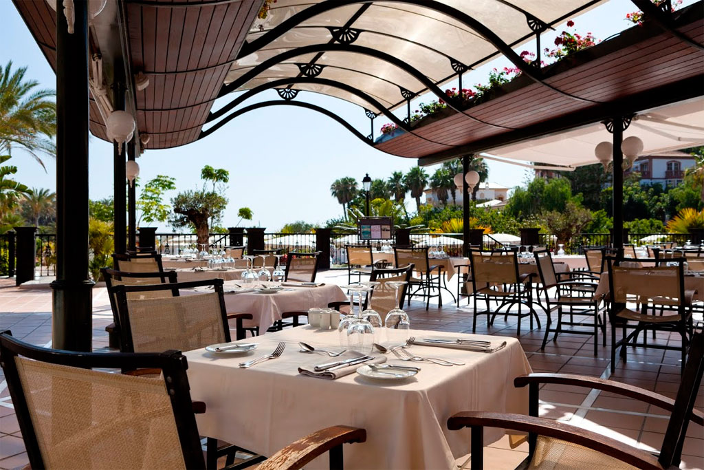 Terraza de restaurante en Tenerife con mesas preparadas y vista al jardín.