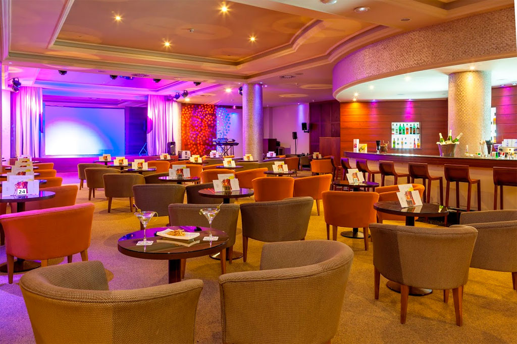 Sala de eventos con sillas, mesas y un bar iluminados en Tenerife.