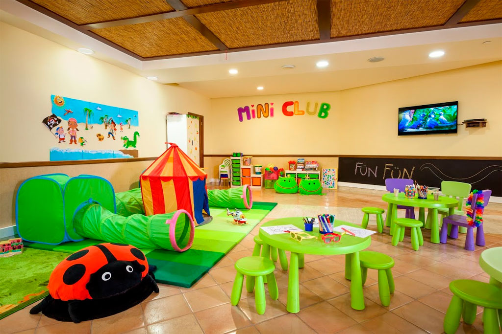 Área de juegos infantil Mini Club en hotel de Tenerife con túneles y mesas de actividades.