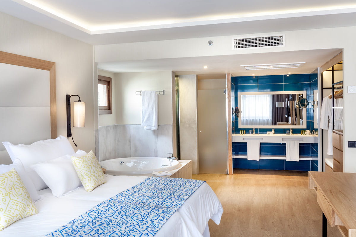 Habitación con cama doble y baño con jacuzzi en un hotel de Tenerife.