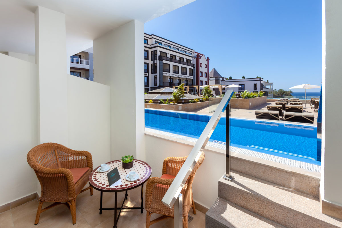 Terraza con sillas y mesa cerca de la piscina en hotel de Tenerife.