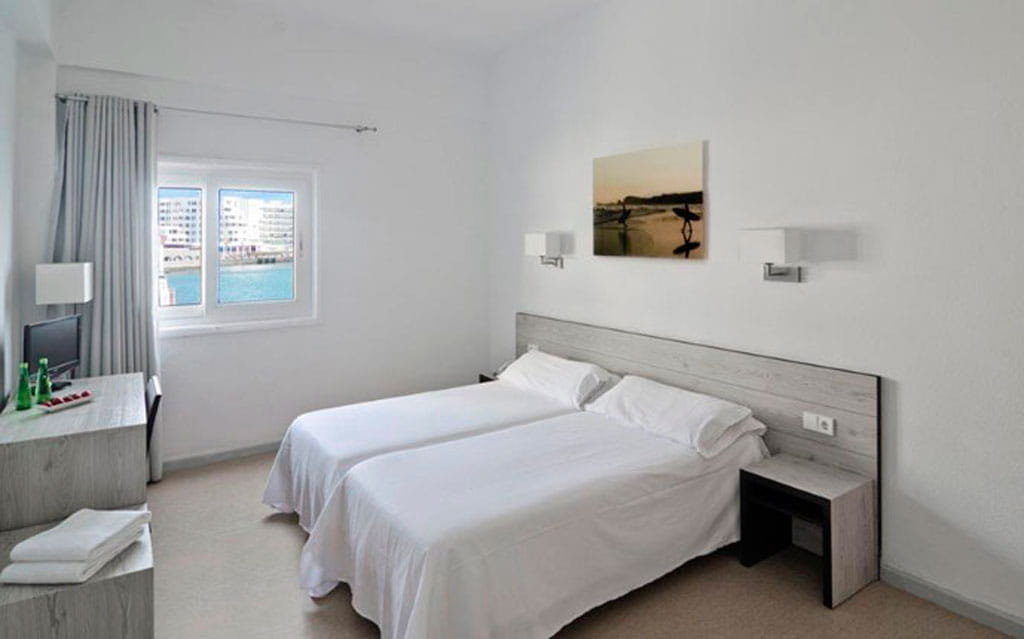 Habitación doble con ventana al mar y decoraciones simples en Tenerife.