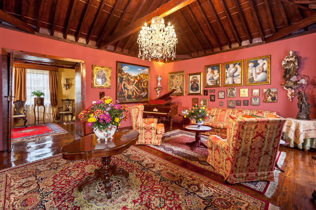 Sala de estar elegante con sofás, piano, flores y cuadros en Tenerife.