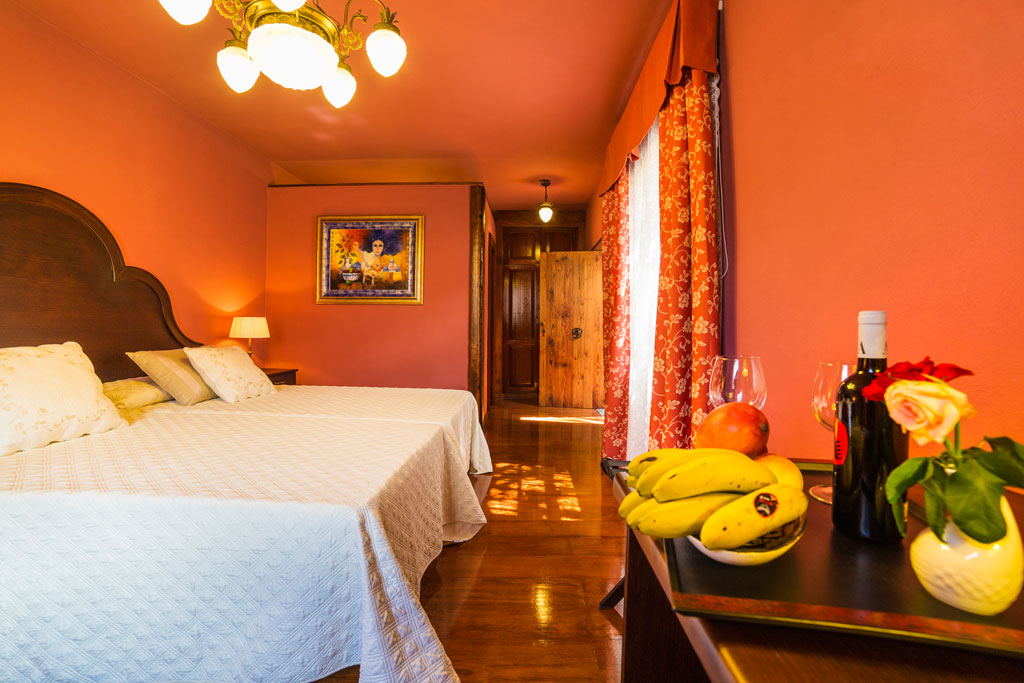 Habitación de hotel en Tenerife con cama doble y mesa con frutas y vino.