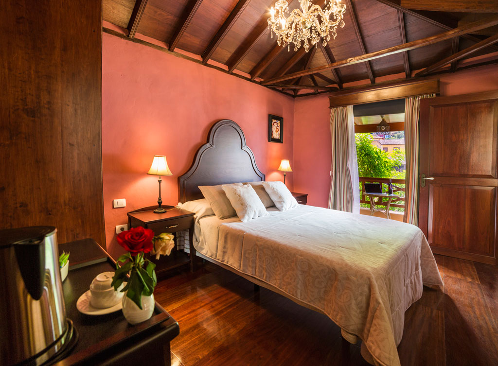 Habitación con cama doble, lámparas y vista al jardín en un alojamiento en Tenerife.