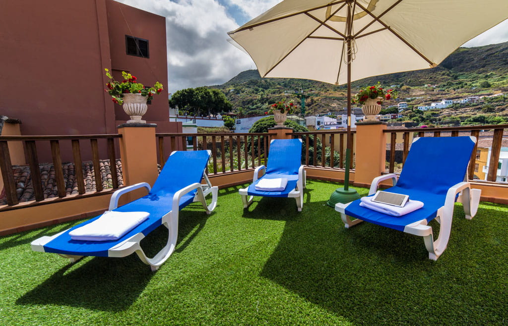 Tumbonas azules con sombrilla en terraza de Garachico, Tenerife.