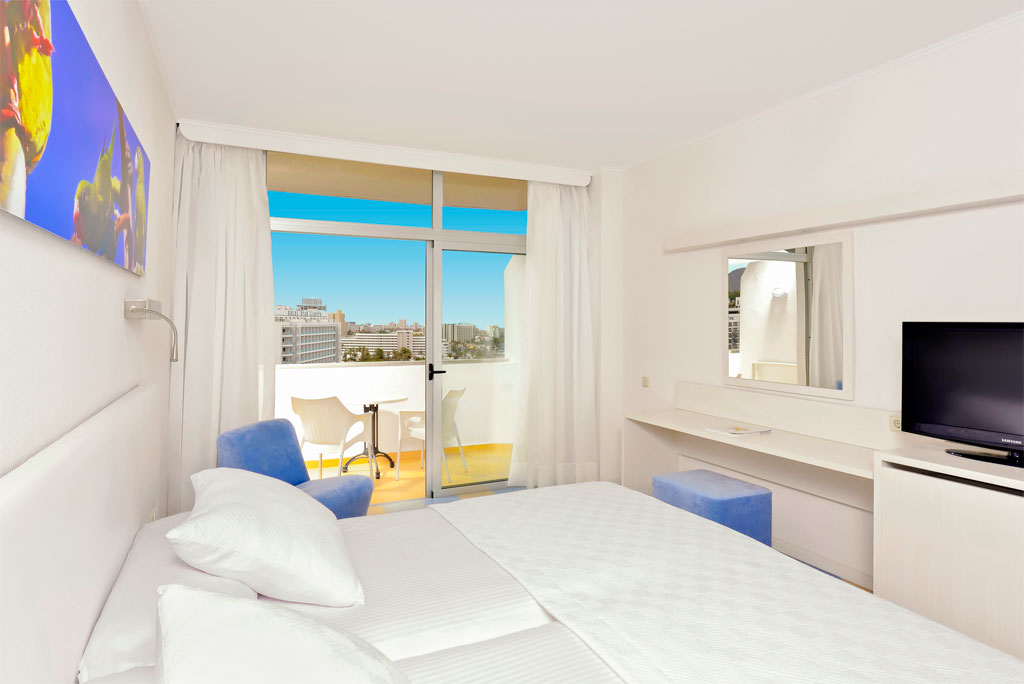 Habitación de hotel en Tenerife con balcón y vista a la ciudad.