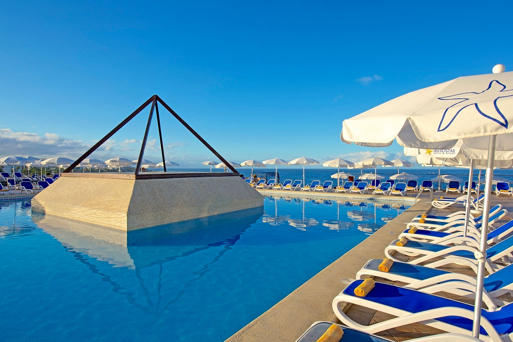 Piscina con sombrillas y tumbonas en complejo hotelero en Tenerife.