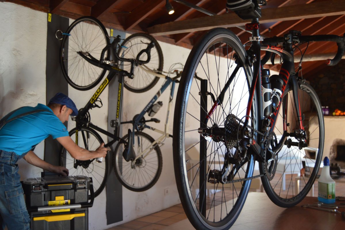 Hombre reparando bicicletas colgadas en taller de El Médano, Tenerife.