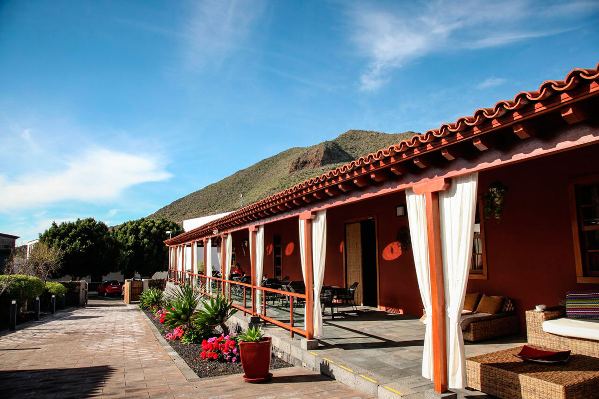 Jardín y terraza en casa rústica en Vilaflor, Tenerife, con montaña al fondo.