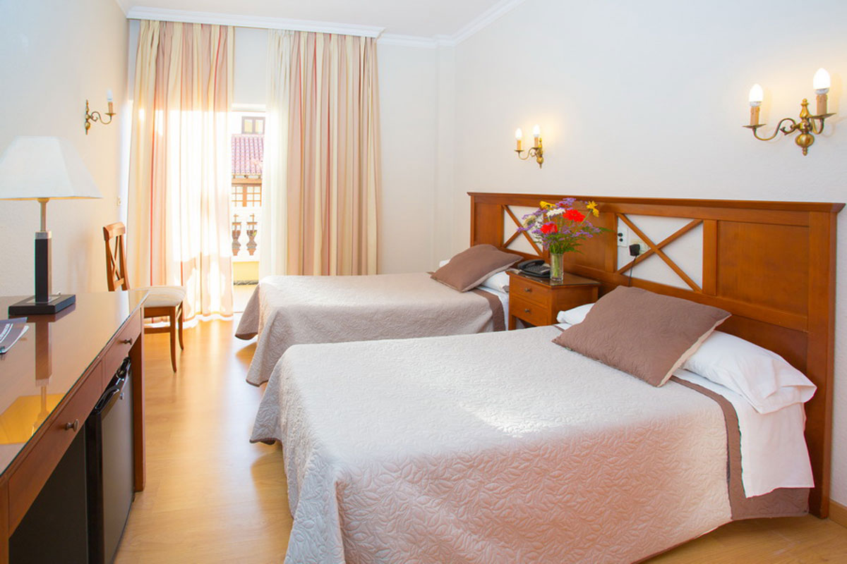 Habitación doble con balcón en hotel de Tenerife, decoración clásica y flores en mesita.