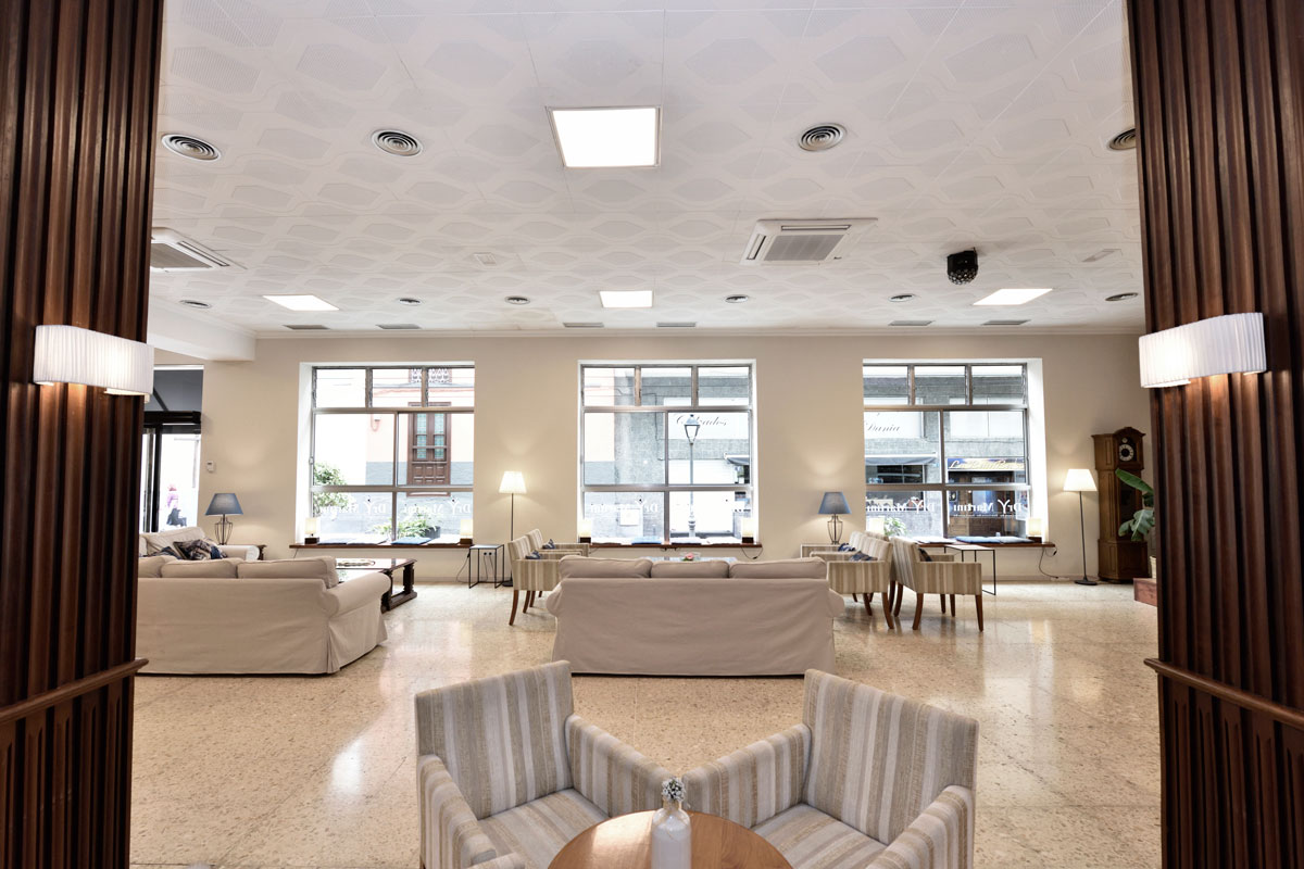 Sala de estar con sillones y lámparas en Tenerife, frente a ventanales grandes.
