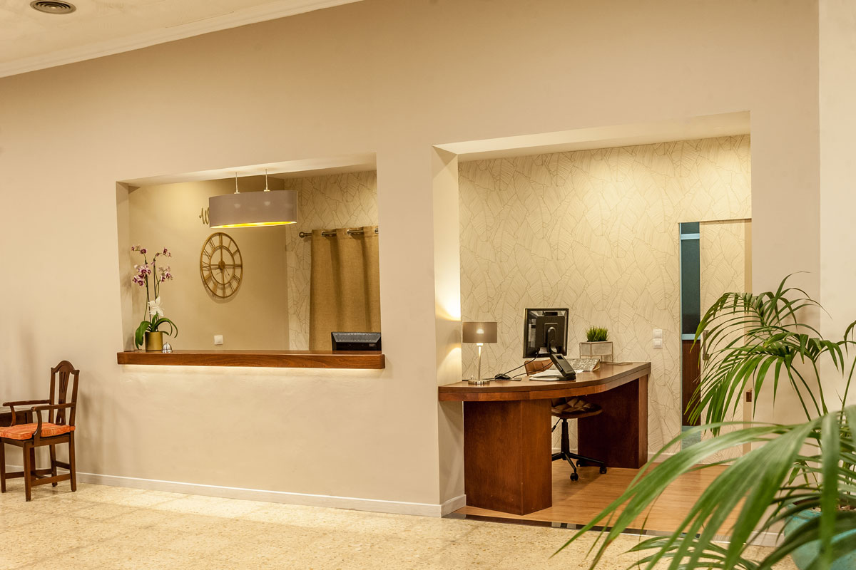 Recepción de hotel en Tenerife con mostrador de madera y computadora.