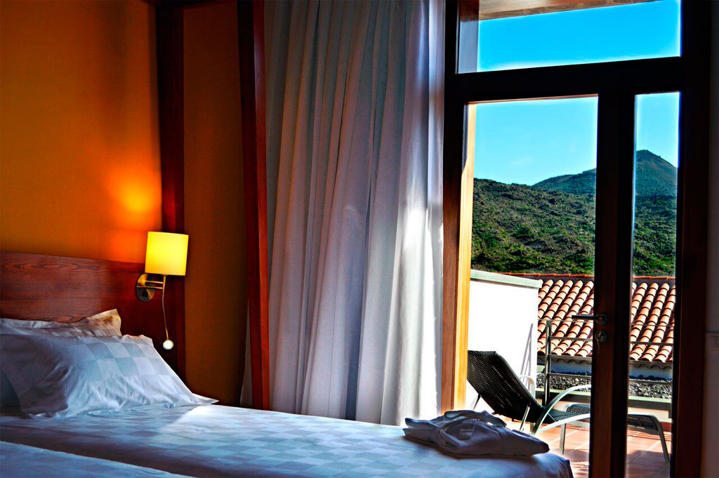Habitación con vistas a las montañas de Tenerife y terraza con silla.