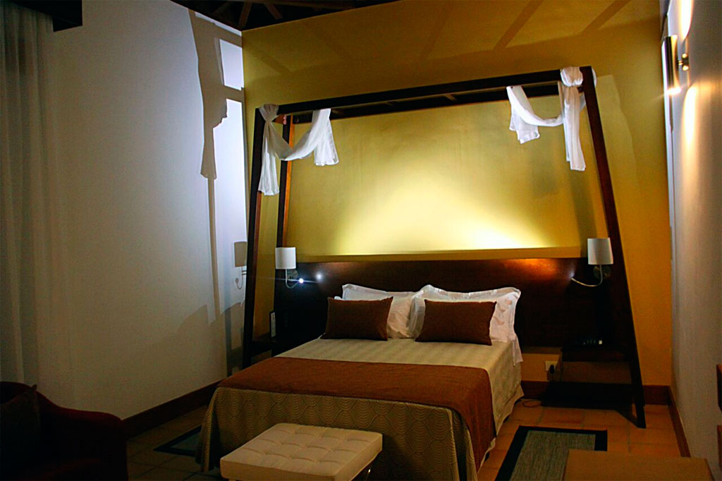 Habitación con cama doble y cabecero con telas colgantes en Tenerife.