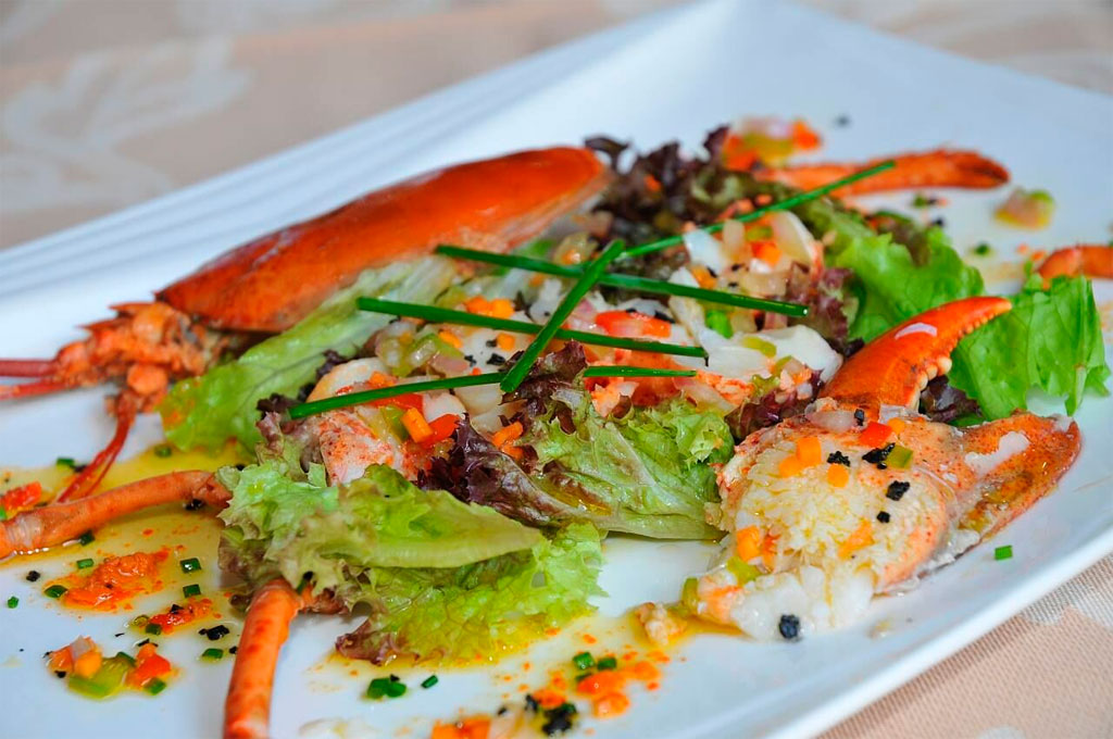 Langosta con ensalada fresca en plato blanco en Tenerife.