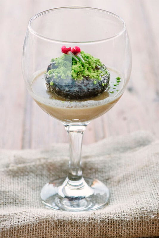 Postre en copa de cristal con base cremosa y bizcocho verde en un restaurante de Tenerife.